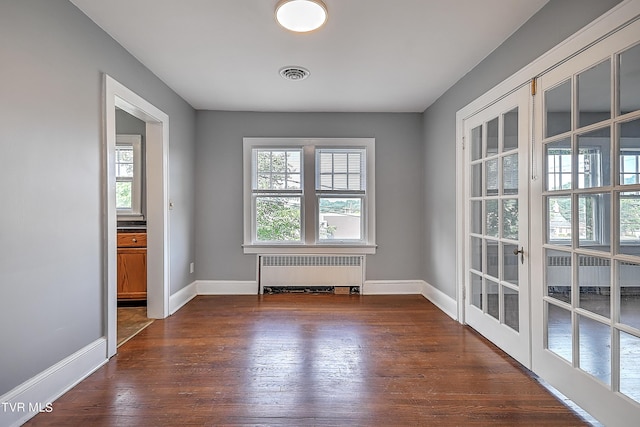 unfurnished room with french doors, baseboards, radiator heating unit, visible vents, and dark wood-style floors