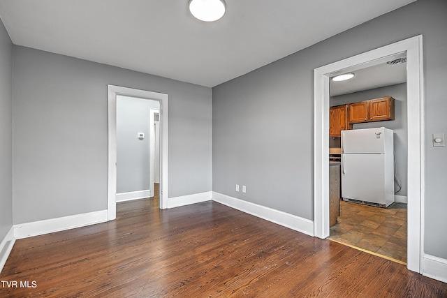 spare room featuring baseboards and dark wood-type flooring
