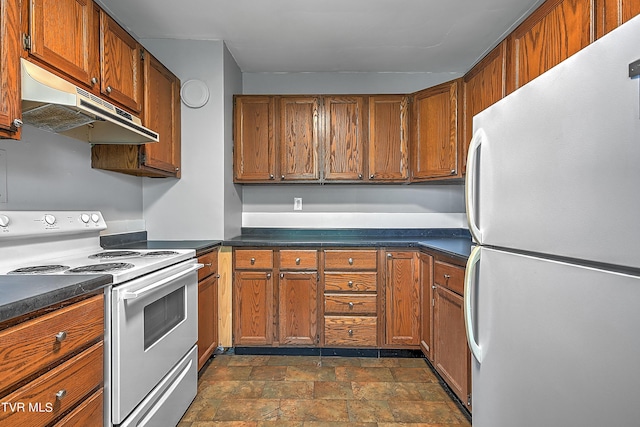kitchen with stone finish flooring, dark countertops, brown cabinetry, white appliances, and under cabinet range hood