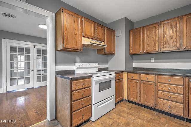kitchen featuring under cabinet range hood, white range with electric stovetop, dark countertops, and visible vents