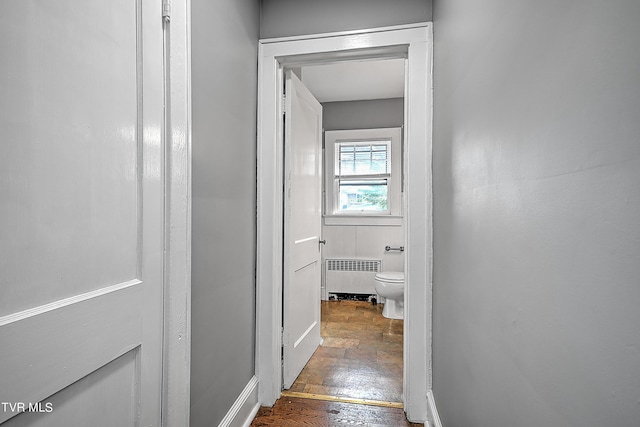 hallway with baseboards, radiator heating unit, and wood finished floors