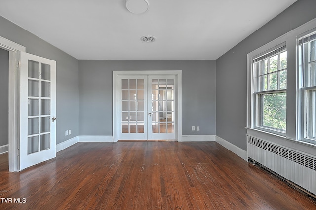 spare room with french doors, radiator heating unit, visible vents, dark wood finished floors, and baseboards