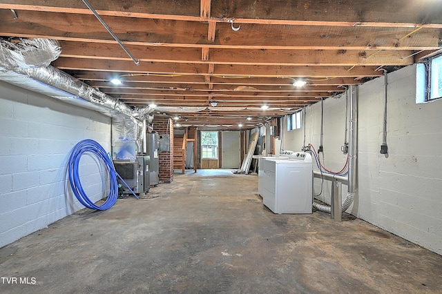 below grade area featuring washer and dryer, water heater, concrete block wall, and heating unit