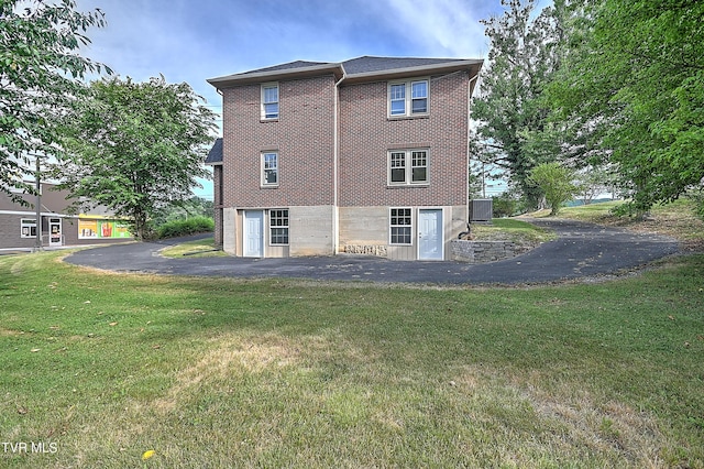 rear view of house with a lawn and brick siding