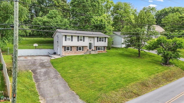 raised ranch with brick siding, a front lawn, and aphalt driveway