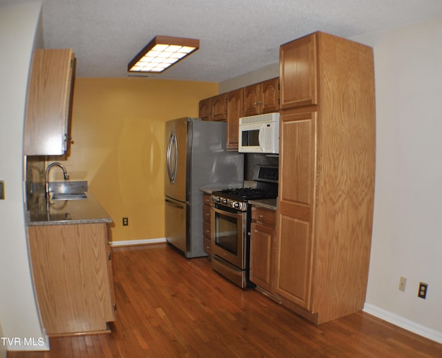 2700 Indian Ridge Rd Unit 23, Johnson City, TN 37604 - kitchen with stainless steel appliances, a sink, dark wood-style flooring, baseboards, and brown cabinets