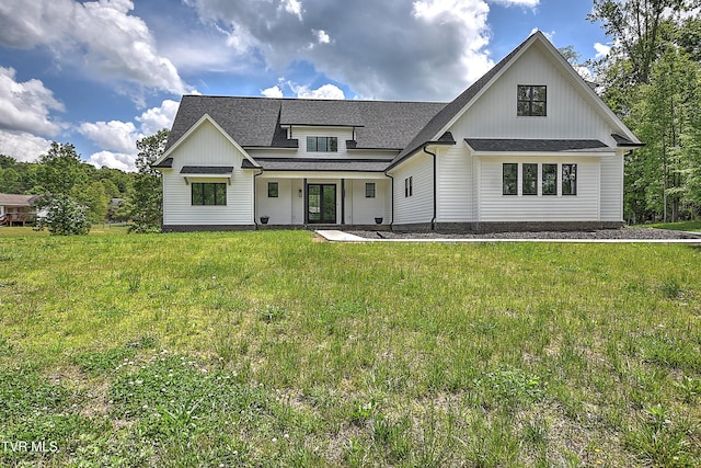 modern farmhouse featuring a front lawn, a shingled roof, and covered porch