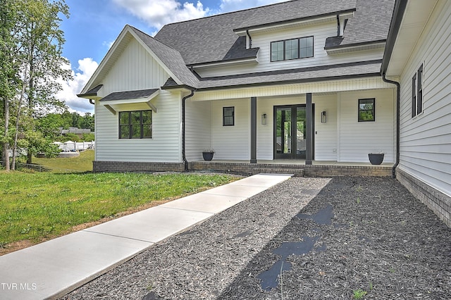 view of front facade featuring a front yard, roof with shingles, covered porch, and board and batten siding
