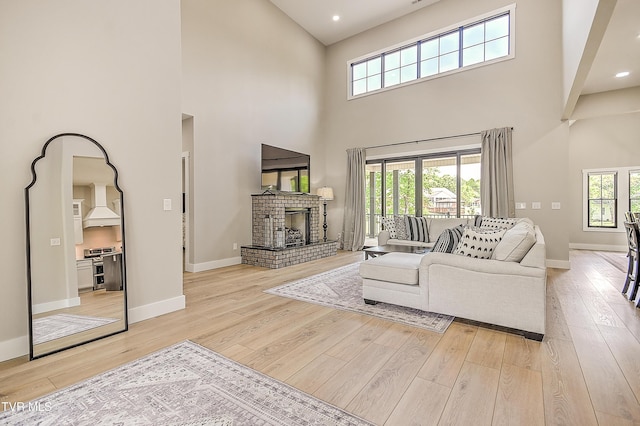living room featuring light wood finished floors, a high ceiling, and baseboards