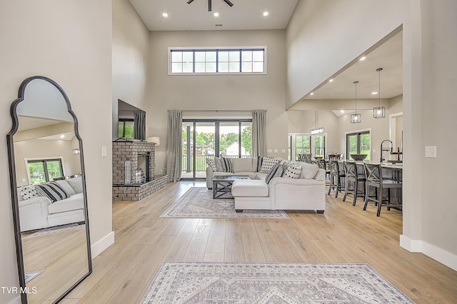 living room featuring light wood finished floors, baseboards, a towering ceiling, and a fireplace