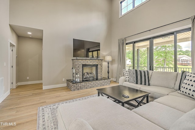 living room with wood finished floors, baseboards, a towering ceiling, and a fireplace