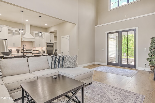 living area with french doors, baseboards, and a healthy amount of sunlight