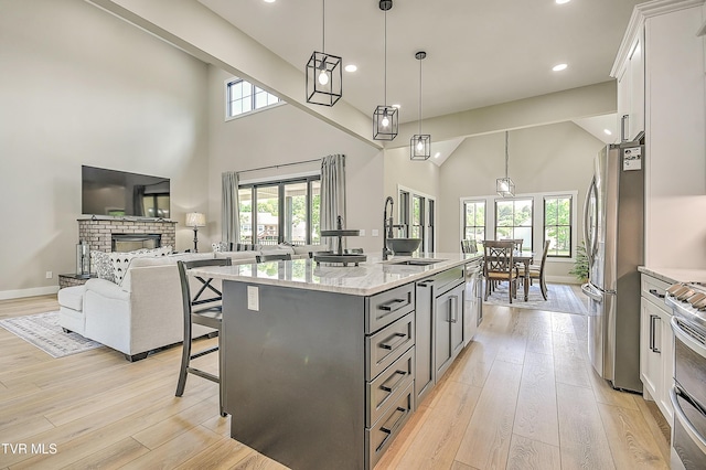 kitchen with appliances with stainless steel finishes, light wood-style flooring, a breakfast bar area, and a sink