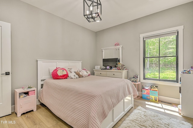 bedroom with an inviting chandelier, light wood-style flooring, and visible vents