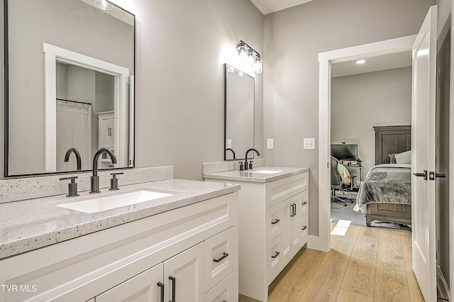 bathroom with connected bathroom, two vanities, a sink, and wood finished floors