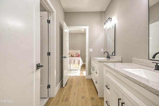 ensuite bathroom with a sink, two vanities, wood-type flooring, and connected bathroom