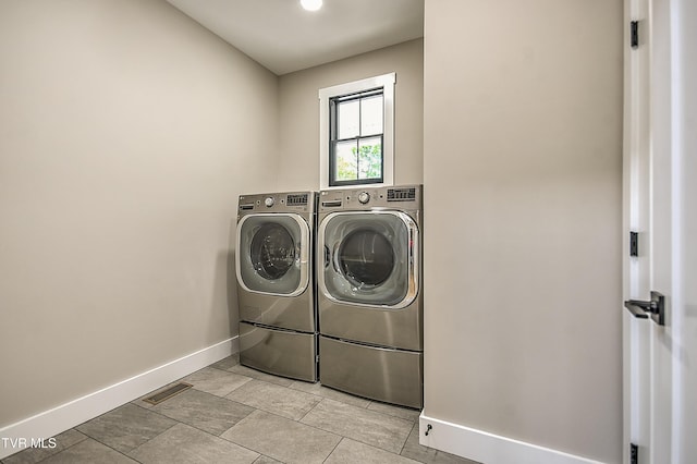 clothes washing area featuring laundry area, washer and clothes dryer, visible vents, and baseboards