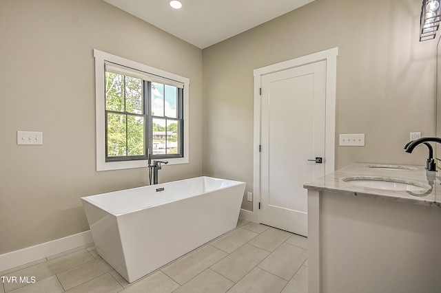 bathroom featuring recessed lighting, a freestanding bath, tile patterned flooring, and a sink