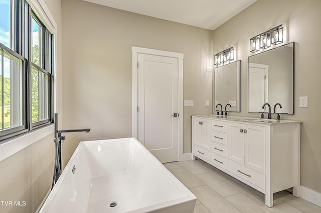 bathroom featuring a sink, a freestanding bath, a healthy amount of sunlight, and tile patterned floors