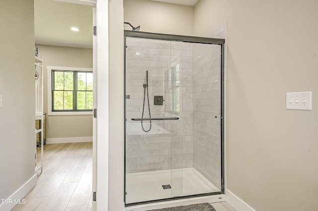 bathroom featuring baseboards, wood finished floors, recessed lighting, and a stall shower