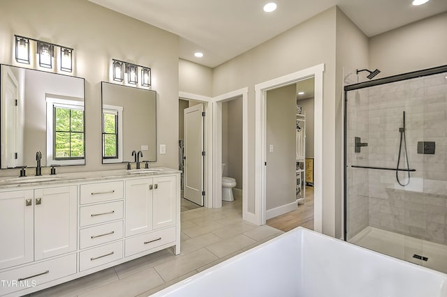 bathroom with recessed lighting, toilet, a shower stall, and a sink