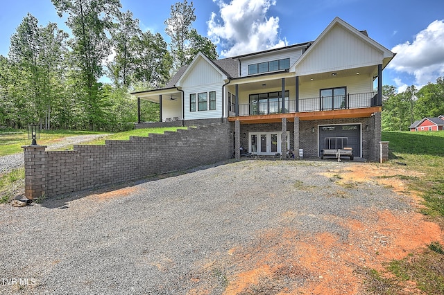 view of front of home featuring brick siding, french doors, a garage, and gravel driveway