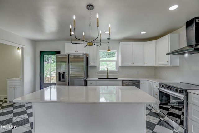 kitchen featuring wall chimney range hood, plenty of natural light, stainless steel appliances, and a sink