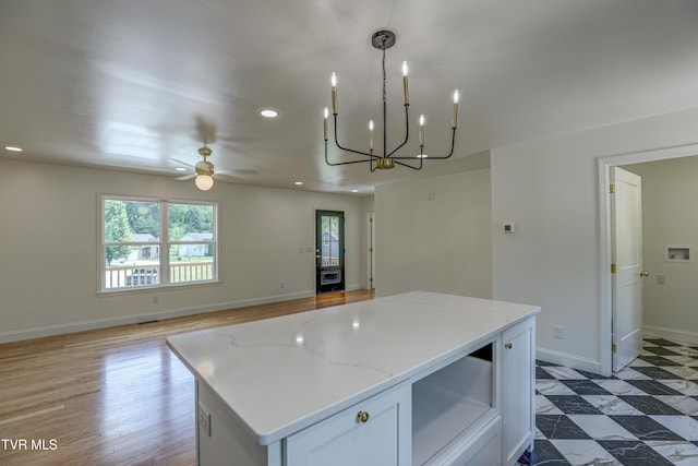 kitchen featuring ceiling fan with notable chandelier, open floor plan, baseboards, a kitchen island, and recessed lighting