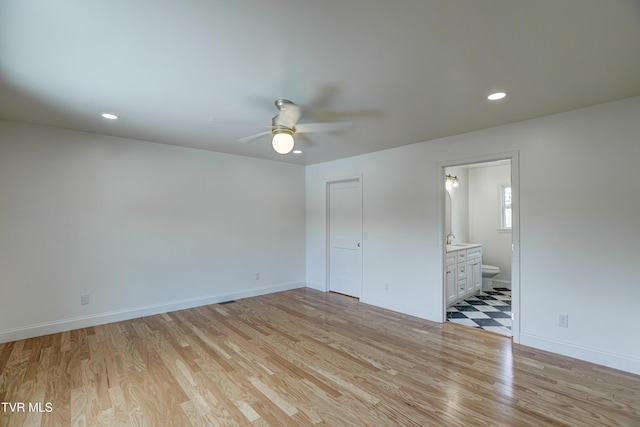 unfurnished bedroom featuring ensuite bath, light wood-style floors, baseboards, and recessed lighting
