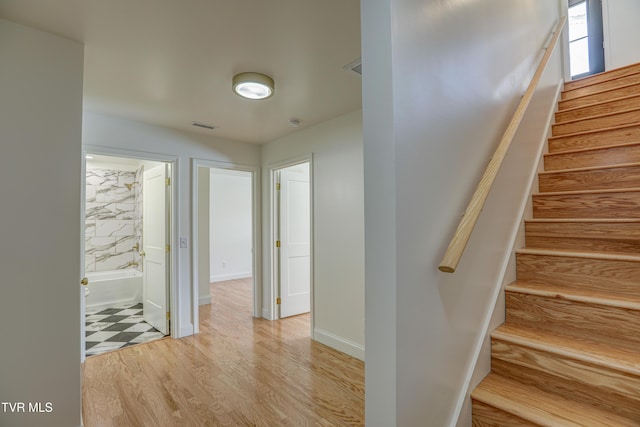 staircase featuring baseboards, visible vents, and wood finished floors