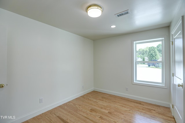 spare room with baseboards, light wood-type flooring, and visible vents