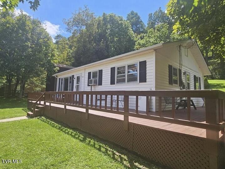rear view of house with a wooden deck and a yard