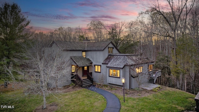 rustic home featuring a chimney, a yard, stairway, and covered porch