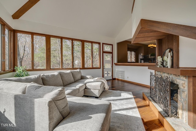 living area with wood finished floors, high vaulted ceiling, visible vents, baseboards, and a stone fireplace