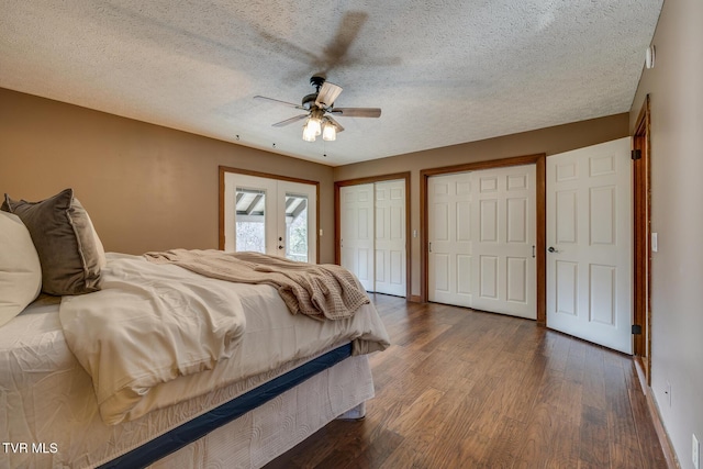 bedroom with a textured ceiling, two closets, and dark wood-style floors