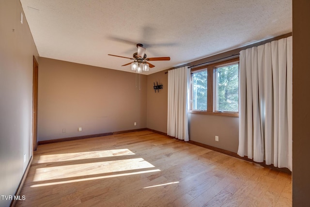 empty room featuring light wood-type flooring, baseboards, a ceiling fan, and a textured ceiling
