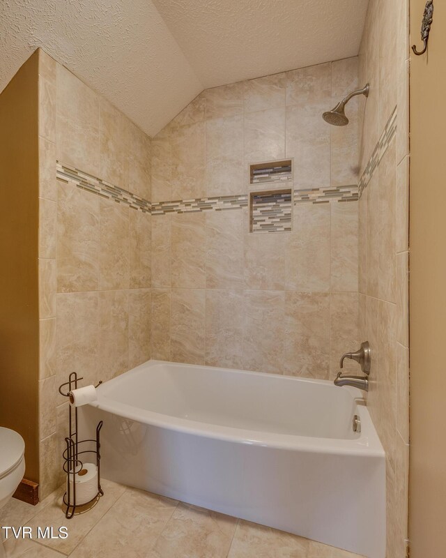 bathroom with toilet,  shower combination, a textured ceiling, tile patterned flooring, and lofted ceiling