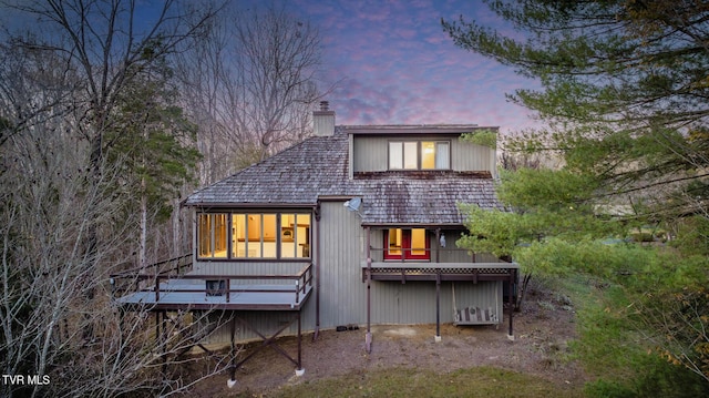 back of house with a chimney and a deck