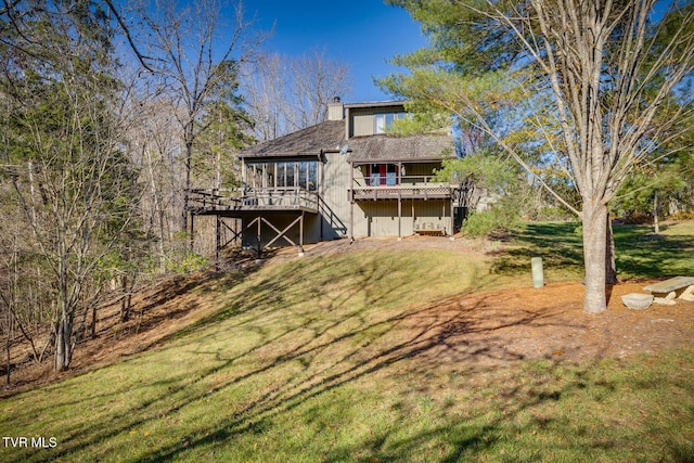 rear view of property with a lawn, a chimney, and a wooden deck