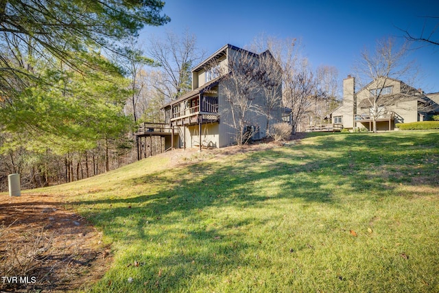 rear view of property with a chimney, a deck, and a lawn
