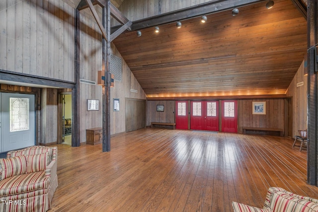 unfurnished living room with wooden ceiling, wooden walls, hardwood / wood-style floors, and high vaulted ceiling