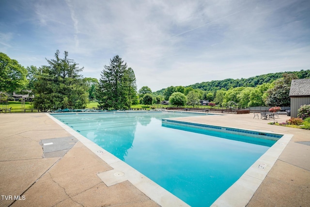 community pool with a patio area and fence