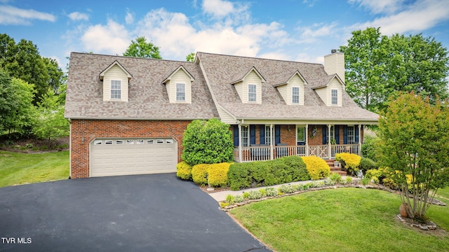 new england style home featuring brick siding, asphalt driveway, covered porch, an attached garage, and a chimney