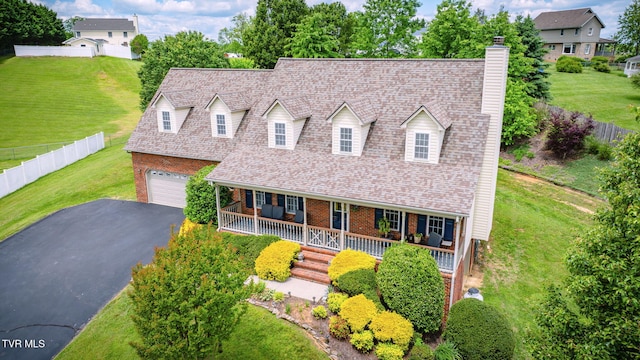 cape cod-style house featuring a porch, a chimney, brick siding, and driveway