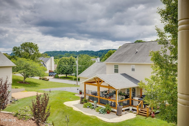 rear view of property featuring a yard, roof with shingles, and a deck