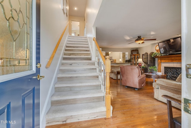 stairs featuring ceiling fan, wood finished floors, a fireplace, baseboards, and recessed lighting