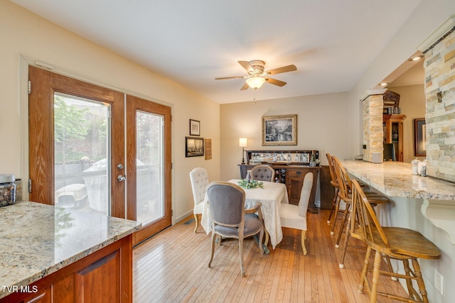 dining room featuring ceiling fan, light wood finished floors, and french doors