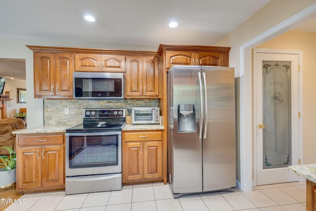 kitchen featuring stainless steel appliances, light stone counters, tasteful backsplash, brown cabinets, and recessed lighting