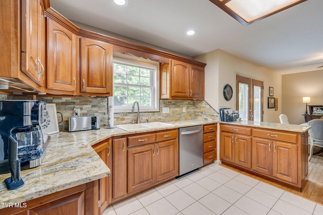 kitchen with dishwasher, a sink, a peninsula, brown cabinets, and decorative backsplash
