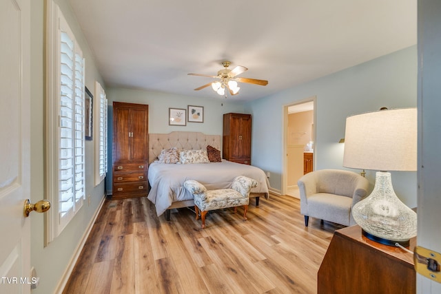 bedroom with light wood finished floors, baseboards, a ceiling fan, and ensuite bath